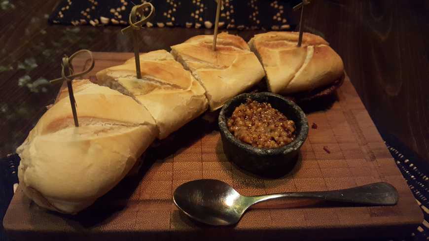 Sanduíche de pastrami de wagyu na baguette com queijo gruyère, marmelada de cebola, mostarda da casa e alface americana.