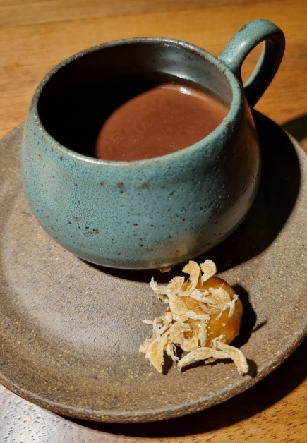 Inusitado chocolate quente picante com macadâmia caramelizada com camarãozinho seco fecha o menu degustação do Notiê!