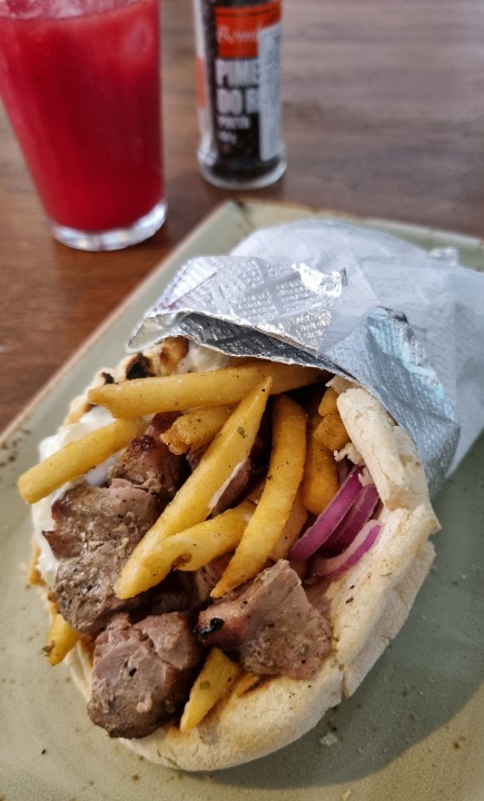 Souvláki: sanduíche de pernil no pão pita, tomate, cebola, tzatziki e batata frita